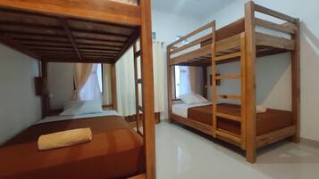 Una habitación con literas, una ventana con cortinas y una cama con una toalla.
