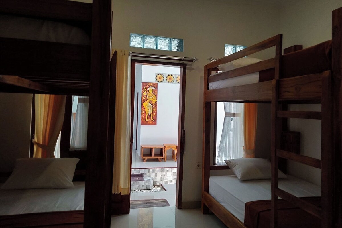 A room with two bunk beds, a small table, and a chair.