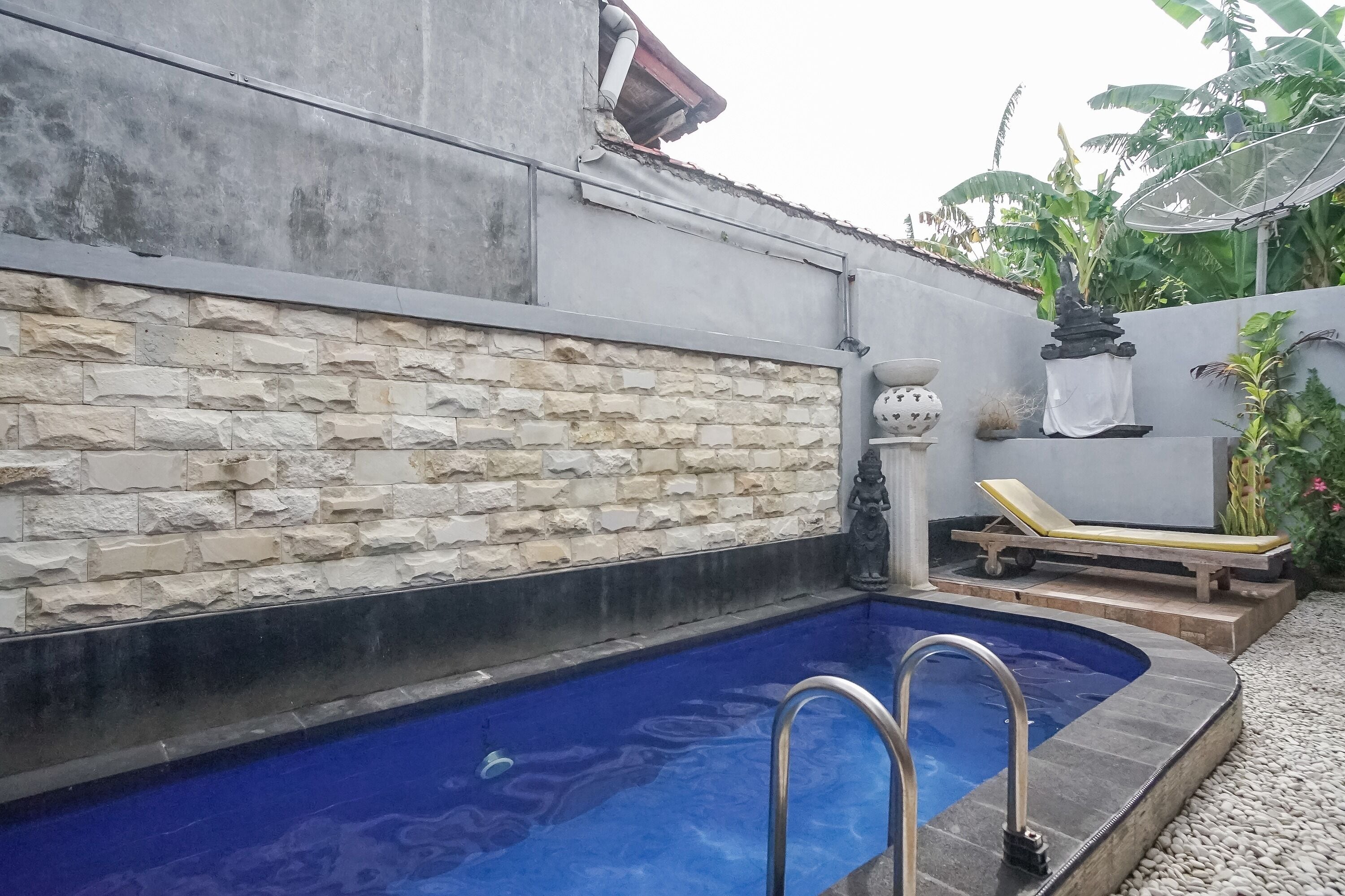 A swimming pool with stone walls and a lounge chair.