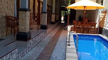 Een buitenzwembad, ligstoelen bij het zwembad