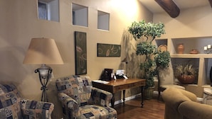 Un salón acogedor con sillones estampados, una mesa de centro de madera y una planta grande en maceta.
