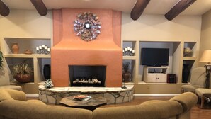 Una sala de estar acogedora con chimenea de piedra, asientos cómodos y un televisor.