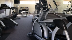 Un gimnasio con cintas de correr, máquinas elípticas y equipo de pesas.