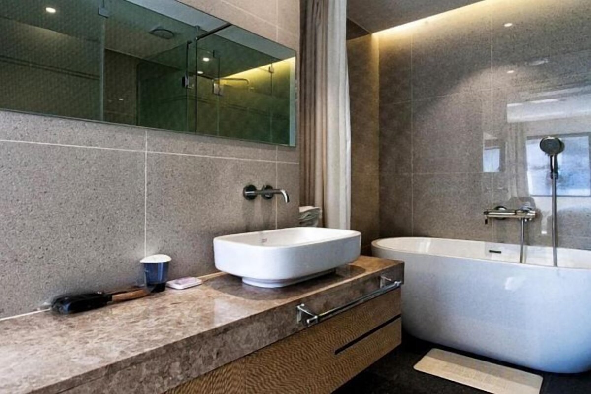 A modern bathroom with a large bathtub, a sink, and a mirror.