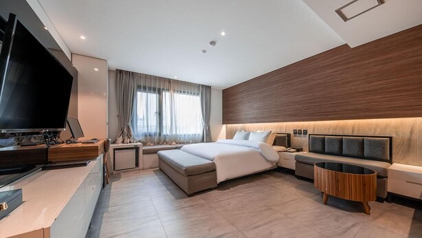 Une chambre d’hôtel moderne équipée d’un lit, de tables de chevet, d’une télévision et d’un coin salon.