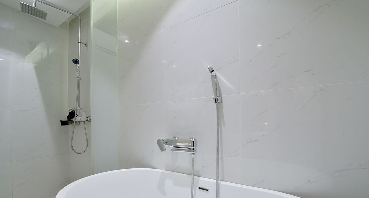 A modern bathroom with a freestanding bathtub, a glass-enclosed shower area, and white marble walls.