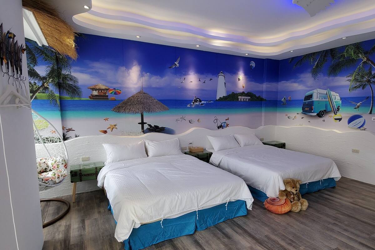 A room with two beds, a hammock, and a mural of a beach scene.