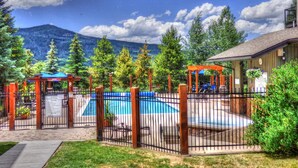 A backyard with a swimming pool, wooden pergolas, and a mountain backdrop. - ⭐️ 2 Level Unit w/ Pool ⎮Hot Tubs ⎮Private Deck (Steamboat Springs)