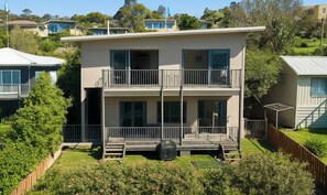 Un immeuble de deux étages doté d’un balcon à l’étage supérieur, entouré de verdure et d’autres immeubles résidentiels.