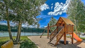 A playground with a wooden structure, a slide, and a bench. - Homey Hideaway Chalet in family friendly Tiger Run, mins from Breckenridge (Breckenridge)