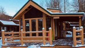 A wooden lodge with a welcoming sign, a covered entrance, and a snow-covered deck. - Homey Hideaway Chalet in family friendly Tiger Run, mins from Breckenridge (Breckenridge)