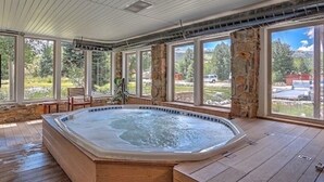 A hot tub in a room with large windows and stone pillars. - Homey Hideaway Chalet in family friendly Tiger Run, mins from Breckenridge (Breckenridge)