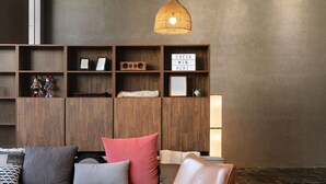 A modern living room with a grey sofa, a brown leather chair, and a wooden shelving unit with various items. - LACOZi STAY Seoul (Seoul)