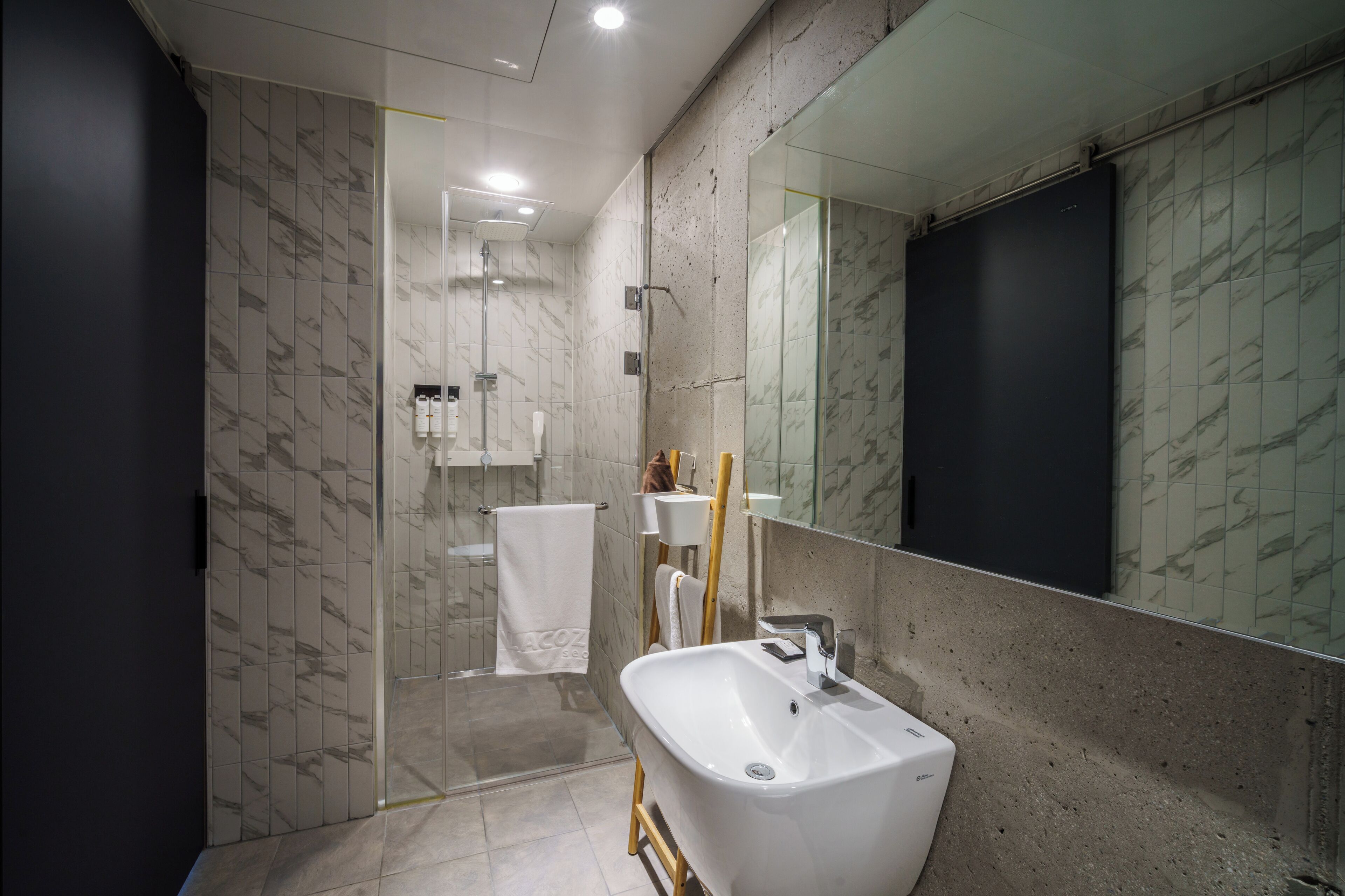 A modern bathroom with a large mirror, a white sink, and a shower area.
