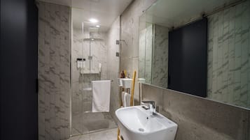 A modern bathroom with a large mirror, a white sink, and a shower area.