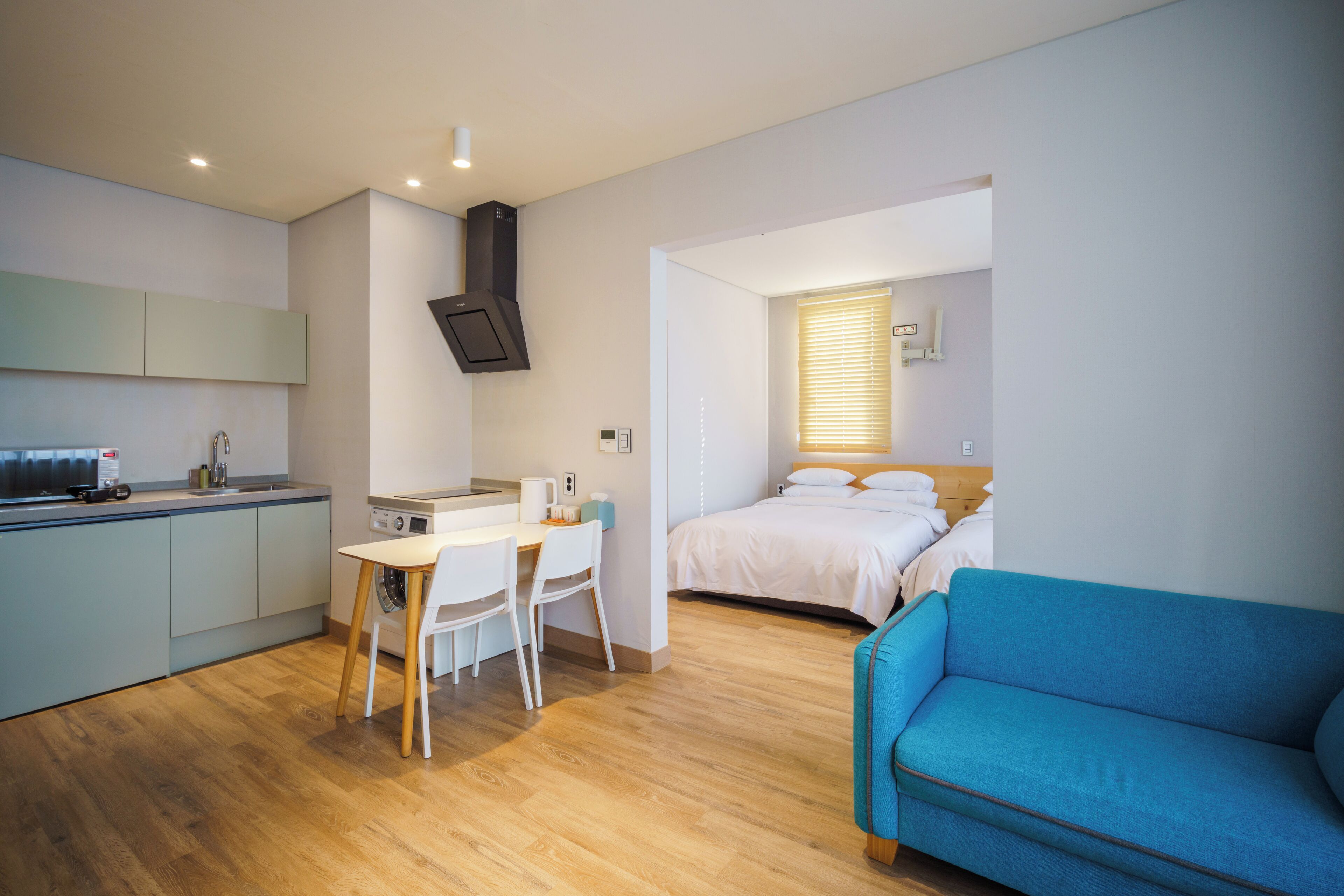 A modern, compact room with a kitchenette, a dining area, and a bed.