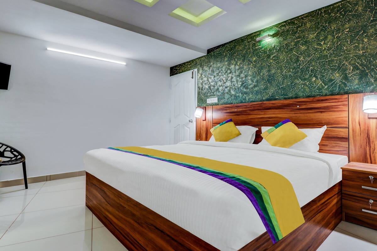 A modern bedroom with a wooden bed frame, a green marble wall, and a white ceiling with recessed lighting.
