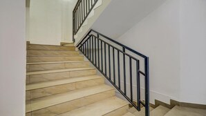 A staircase with beige steps and black metal railings. - Itsy Hotels Dew Dreams (Aluva)