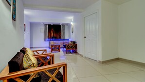 A living room with a sofa, chairs, a coffee table, and a TV. - Itsy Hotels Dew Dreams (Aluva)