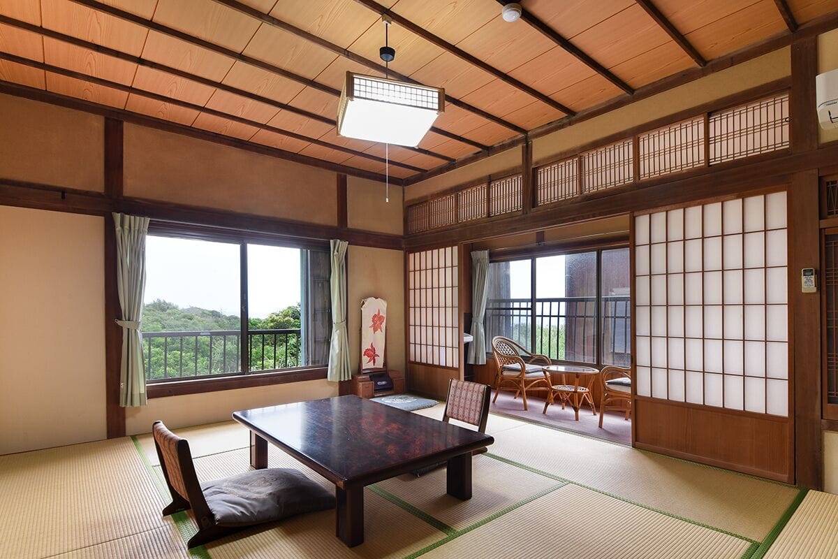 A traditional Japanese room with tatami flooring, a low table, and sliding doors.