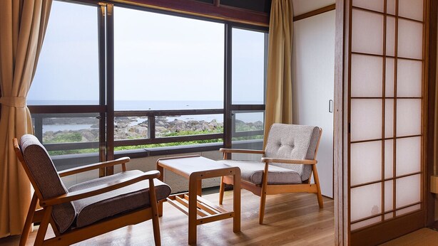 A traditional Japanese room with tatami flooring, a low table, two chairs, and a shoji screen. - Misaki Kanko Hotel (Muroto)