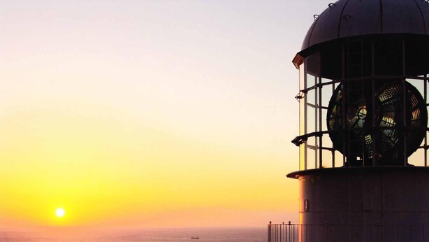 A lighthouse with a large circular lens and a balcony, overlooking a body of water during sunset. - Misaki Kanko Hotel (Muroto)