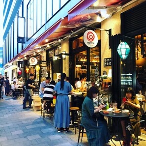A street with outdoor seating at a restaurant with a 'merca' sign.