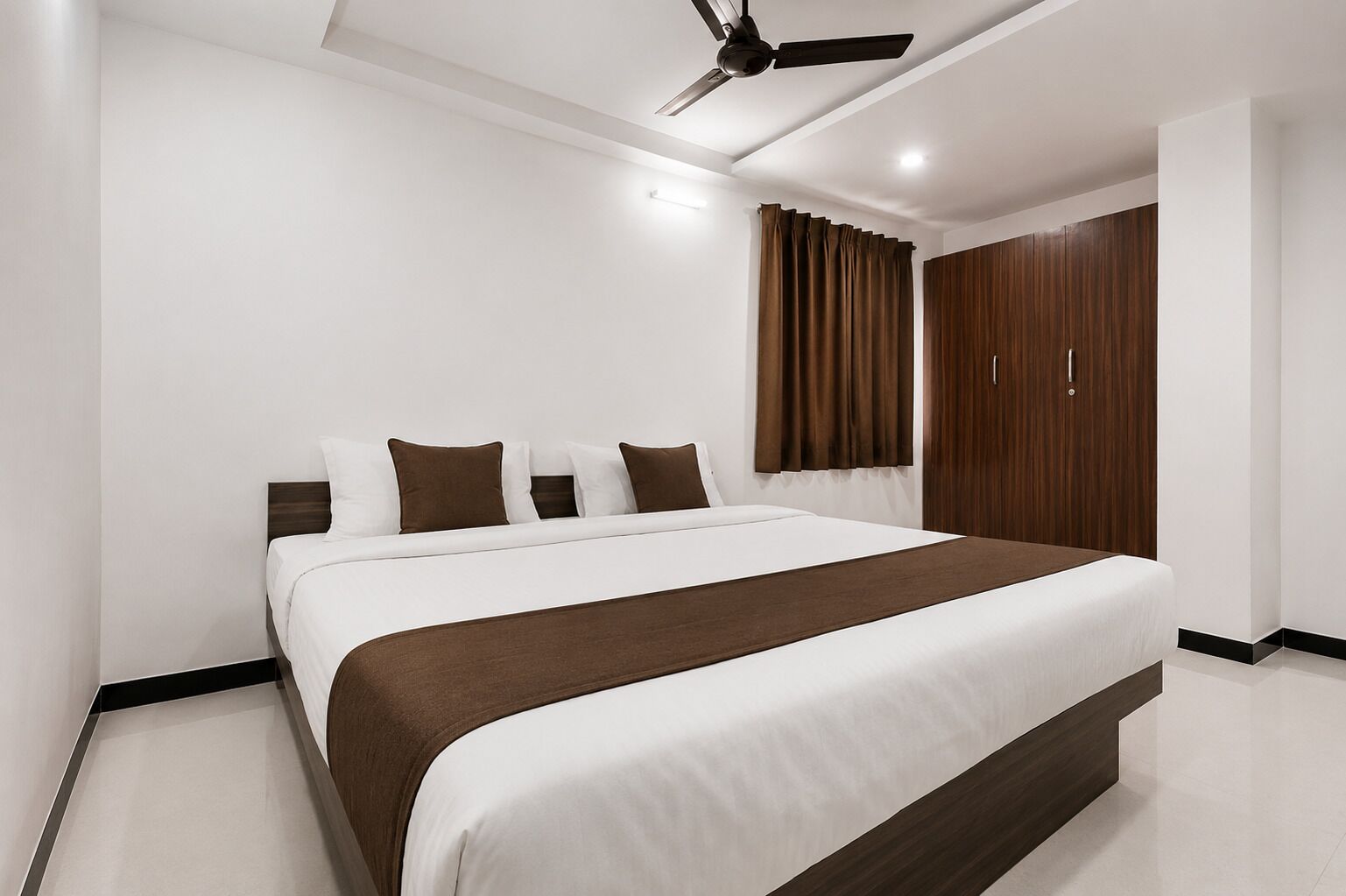 Un dormitorio moderno con una cama grande, ventilador de techo y armario.