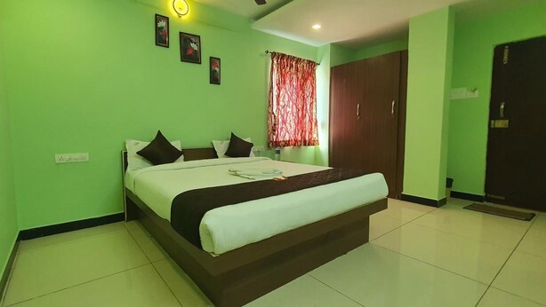 A room with a bed, a wardrobe, and a window with curtains. - JR Stays (Coimbatore)