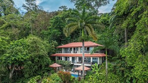 Un bâtiment à deux étages, entouré d’une végétation tropicale luxuriante.