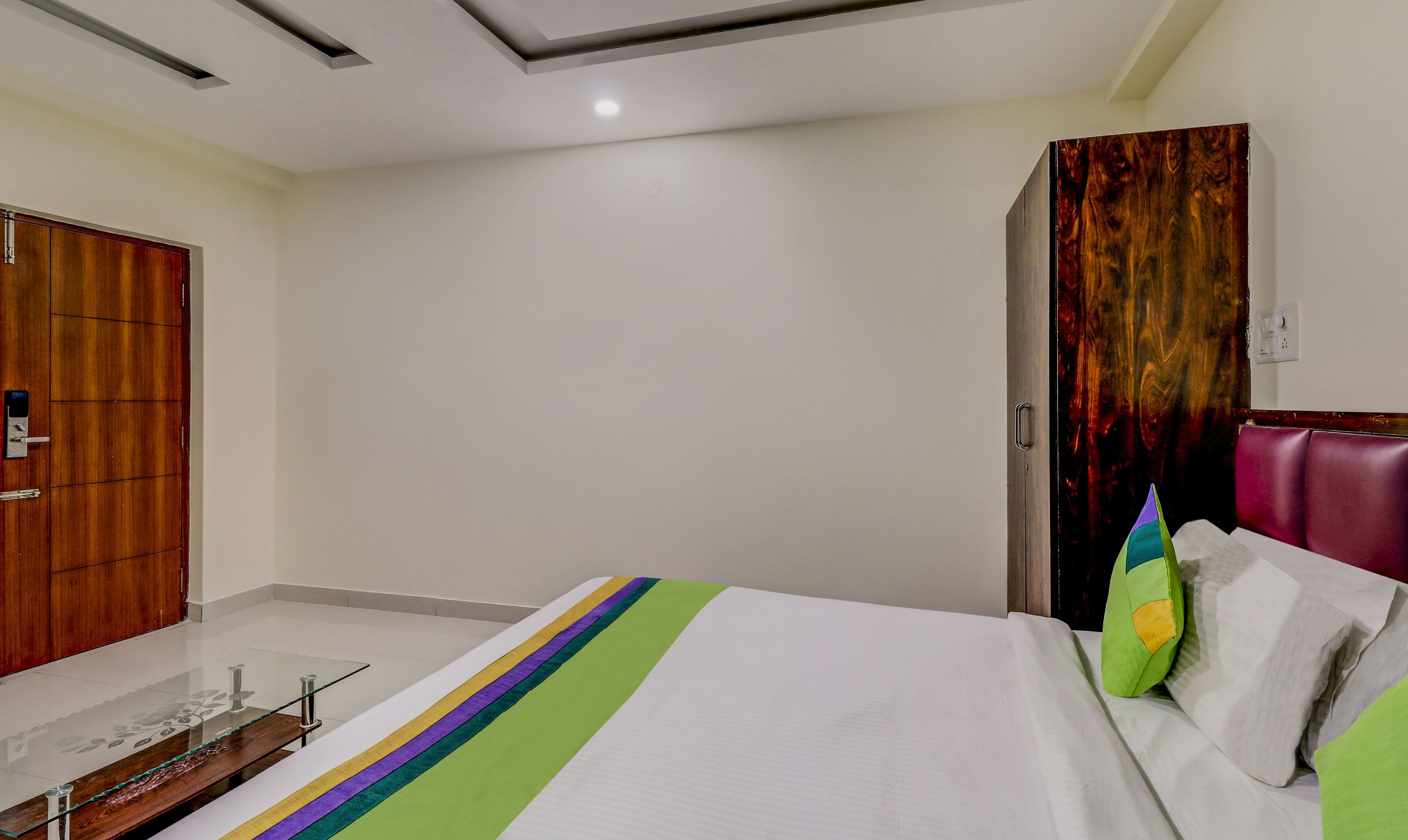 A hotel room with a bed, a wardrobe, a mirror, and a door.