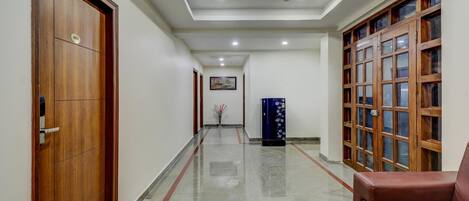 A hallway with wooden doors, a ceiling fan, a framed picture on the wall, and a blue cabinet.
