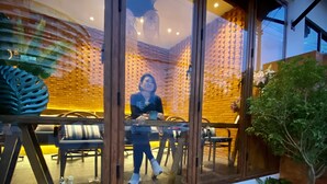 Een modern interieur met een glazen scheiding, een eethoek met stoelen en tafels, en diverse planten en groen.