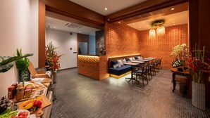 Een restaurant met een bakstenen muur, houten plafond en een zithoek met tafels en stoelen.