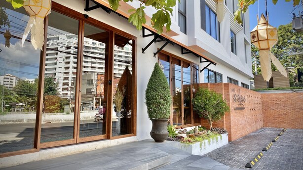 Een modern hotel met grote glazen deuren, een bakstenen muur en een verzorgde tuin.