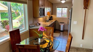 Un coin repas avec une table en verre, des chaises en bois et un vase rempli de fleurs.