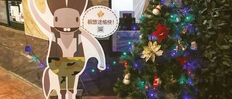 A Christmas tree decorated with ornaments and lights, a cutout of a horse, and a QR code on a sign.
