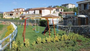 Un quartiere residenziale con un'area giochi, muri in pietra e case con tetti in tegole.
