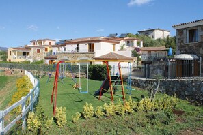 A residential area with a playground, stone buildings, and a clear sky. - Apartment in Tanaunella Budoni with Pool (Tanaunella - Budoni (SS))