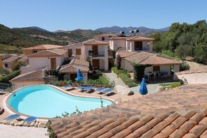 Un resort con piscina, sillas de descanso y montañas al fondo.