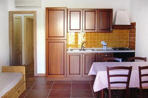 Una cocina compacta con armarios de madera, un lavamanos y una zona de comedor con mesa y sillas.