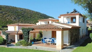 Une maison à deux étages avec un patio, une table à manger et des chaises.