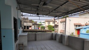 An open terrace with a tiled floor, a small stool, and a metal roof. - Maddy's Den for females (Kolkata)