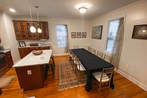 Een keuken met houten kastjes, een centraal eiland en een eethoek met een tafel en stoelen.