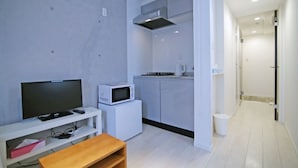 A modern living room with a flat-screen TV, a microwave, and a small table.