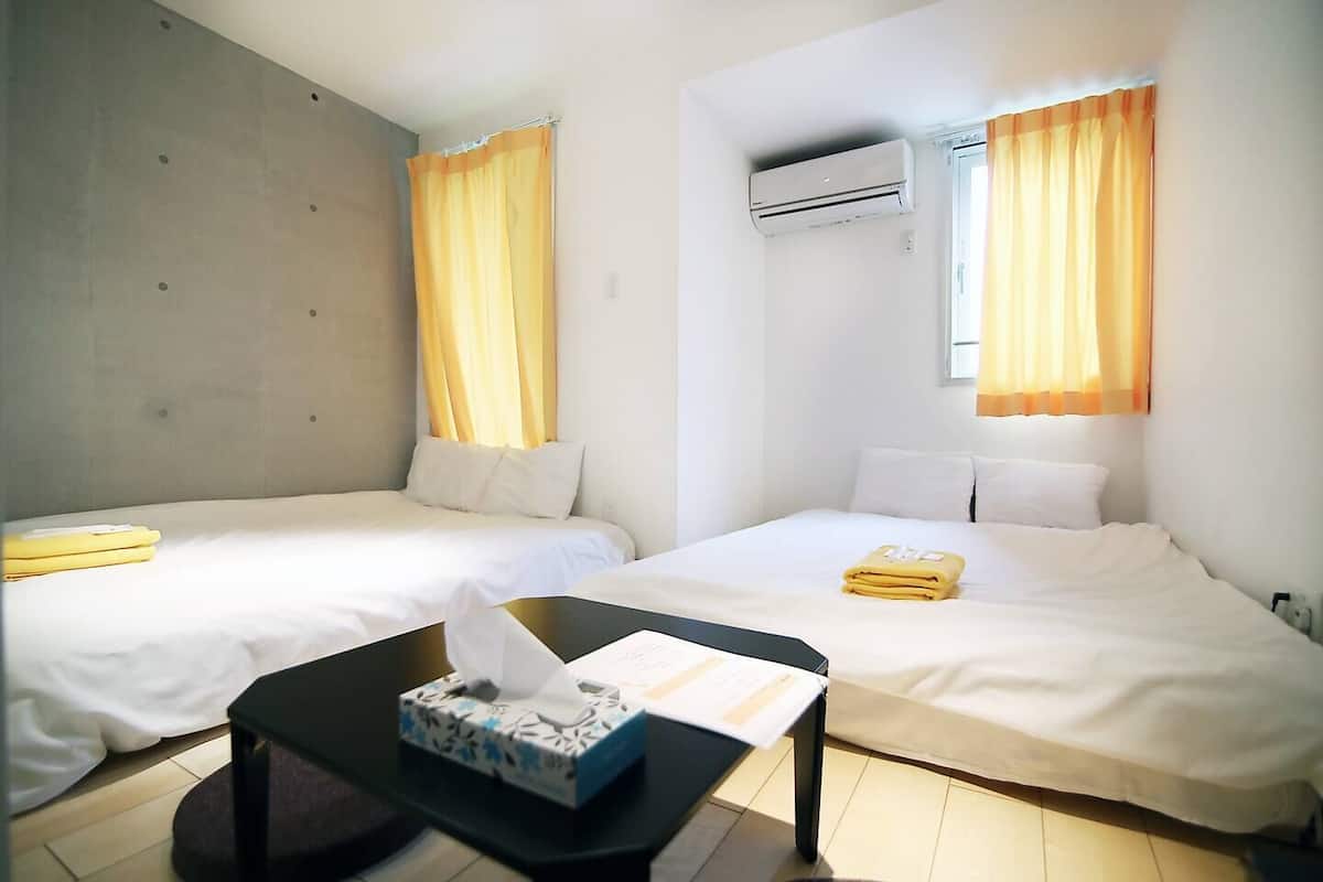 Ein Hotelzimmer mit zwei Betten, einem Tisch und einer Taschentuchbox sowie einer Klimaanlage.