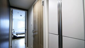 A hallway with a bed, a wardrobe, and a door leading to another room.