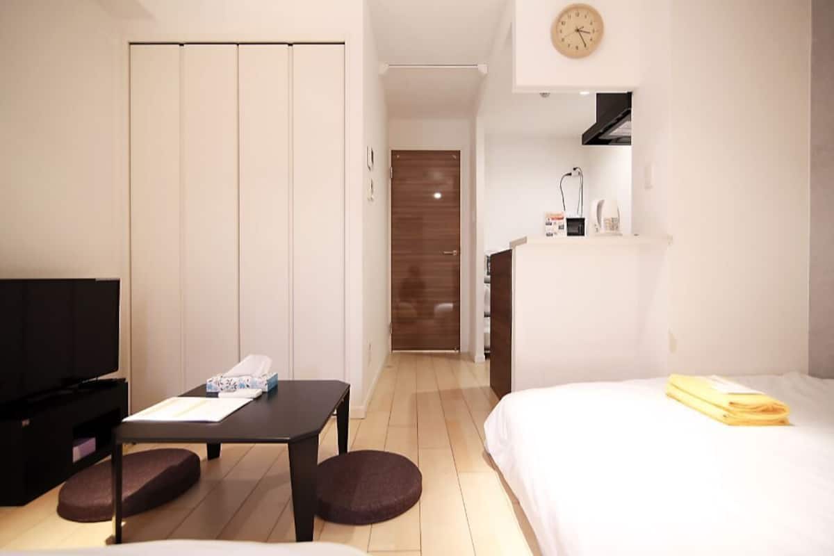 Ein Hotelzimmer mit Bett, Fernseher, Schreibtisch und Kleiderschrank.