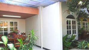 A covered patio area with a dining table and chairs, surrounded by potted plants. - Kanti Kinasih Homestay by The Grand Java (Yogyakarta)