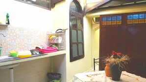 A kitchen with a tiled backsplash, a window, and a door. There is a table with a vase and a chair. - Kanti Kinasih Homestay by The Grand Java (Yogyakarta)